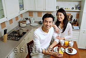 Asia Images Group - Couple in kitchen, smiling at camera