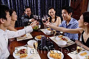 Asia Images Group - Adults at a dinner party, sitting around table, toasting