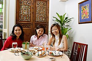 Asia Images Group - Women sitting at table smiling at camera, portrait