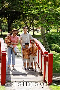 Asia Images Group - Family with three boys in park, standing on bridge, smiling at camera