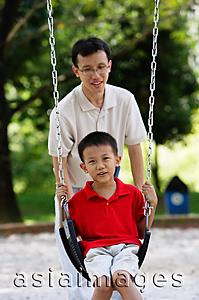 Asia Images Group - Father and son in playground, father pushing son on swing