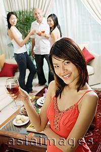 Asia Images Group - Woman holding wine glass, smiling at camera, arms crossed