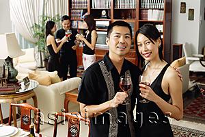 Asia Images Group - Couple in living room, holding wine glasses, smiling at camera