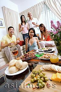 Asia Images Group - Adults in living room, having a party, smiling at camera, food in the foreground
