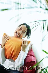 Asia Images Group - Woman holding pillow, smiling, portrait