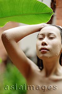 Asia Images Group - Woman taking an outdoor shower, eyes closed