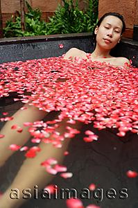 Asia Images Group - Woman in tub filled with floating rose petals