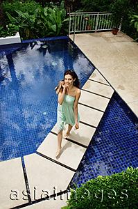 Asia Images Group - Woman in green dress walking across swimming pool, smiling at camera