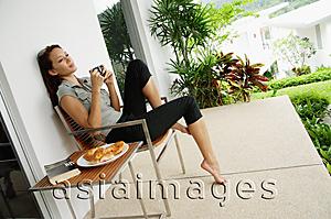 Asia Images Group - Woman having coffee on patio