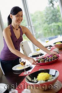 Asia Images Group - Woman setting the dining table, smiling at camera