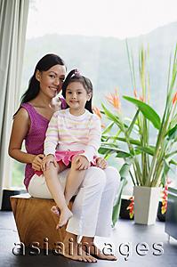 Asia Images Group - Mother with young girl on her lap, smiling at camera