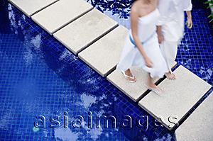 Asia Images Group - Couple walking on walkway across pool