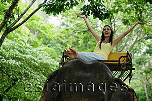 Asia Images Group - Female tourist riding elephant, arms outstretched, Phuket, Thailand