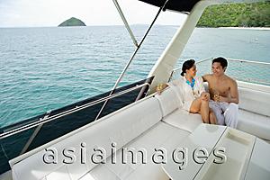 Asia Images Group - Couple sitting on stern of yacht