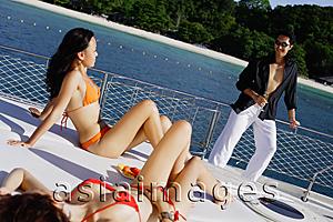 Asia Images Group - Women sitting on boat deck, man standing next to railing, smiling at them