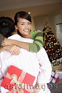 Asia Images Group - Man holding gift behind his back, woman embracing him