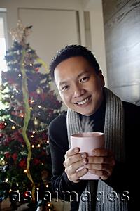 Asia Images Group - Man in sweater and scarf, holding mug, smiling at camera