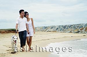 Asia Images Group - Couple walking on beach with Dalmatian