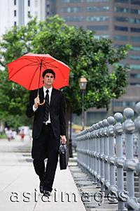 Asia Images Group - Businessman walking with briefcase and red umbrella