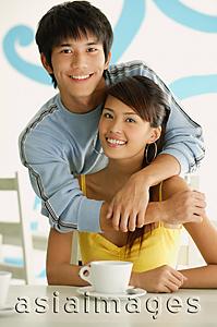 Asia Images Group - Man with arms around seated woman, smiling at camera