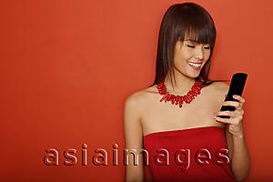 Asia Images Group - Young woman in red tube top using mobile phone