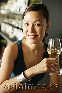Asia Images Group - Woman at bar, holding wine glass, smiling at camera, portrait