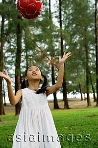 Asia Images Group - Girl in white dress, tossing ball in park