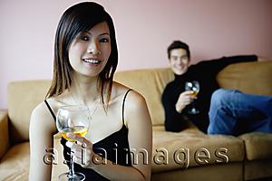 Asia Images Group - Woman holding wine glass, smiling at camera, man in the background