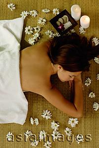 Asia Images Group - Young woman lying on floor, flowers on floor around her, high angle view