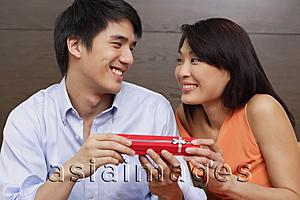 Asia Images Group - Couple side by side, man giving woman present