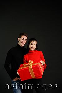 Asia Images Group - Couple standing side by side, woman holding big gift box