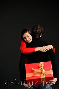 Asia Images Group - Man holding gift behind his box, woman embracing him