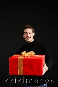 Asia Images Group - Man in black turtleneck, holding wrapped present