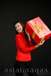 Asia Images Group - Woman in red turtleneck holding gift, looking away