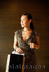 Asia Images Group - Woman carrying shopping bags, looking away