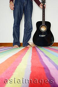 Asia Images Group - Man standing next to guitar, low section