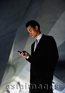 Asia Images Group - Businessman in tunnel, looking at mobile phone