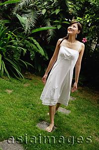 Asia Images Group - Woman in white dress, barefoot in garden