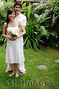 Asia Images Group - Couple in garden, man with arms around woman, woman holding bouquet