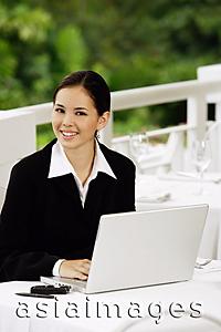 Asia Images Group - Businesswoman sitting with laptop, looking at camera