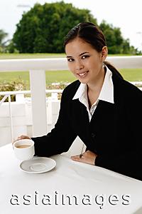Asia Images Group - Businesswoman sitting in cafe, having coffee, looking at camera