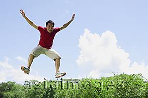 Asia Images Group - Man jumping in mid air, arms outstretched