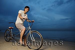 Asia Images Group - Man on beach, sitting on tandem bicycle