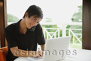Asia Images Group - Man in cafe using laptop and mobile phone