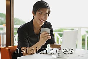 Asia Images Group - Man in cafe using laptop and holding credit card