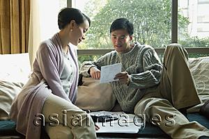 Asia Images Group - Couple in living room, looking at bills