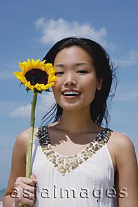 Asia Images Group - Woman holding sunflower stalk, portrait