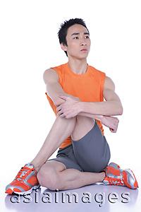 Asia Images Group - Young man sitting on floor, legs and arms crossed