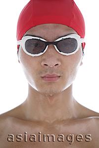 Asia Images Group - Young man wearing swimming goggles and swimming cap, face wet