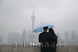 Asia Images Group - Couple using an umbrella looking at Oriental Pearl TV Tower in the background